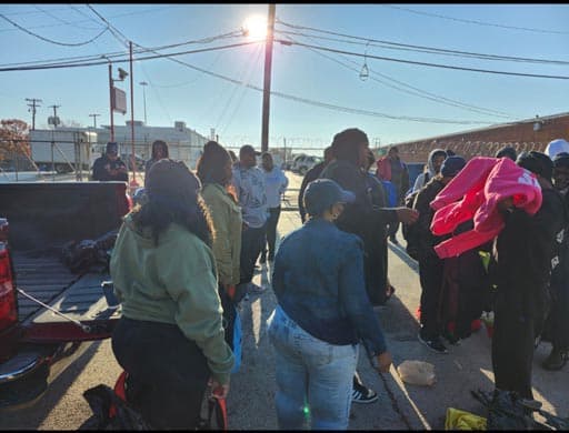 Neighbors gather as volunteers set up the distribution