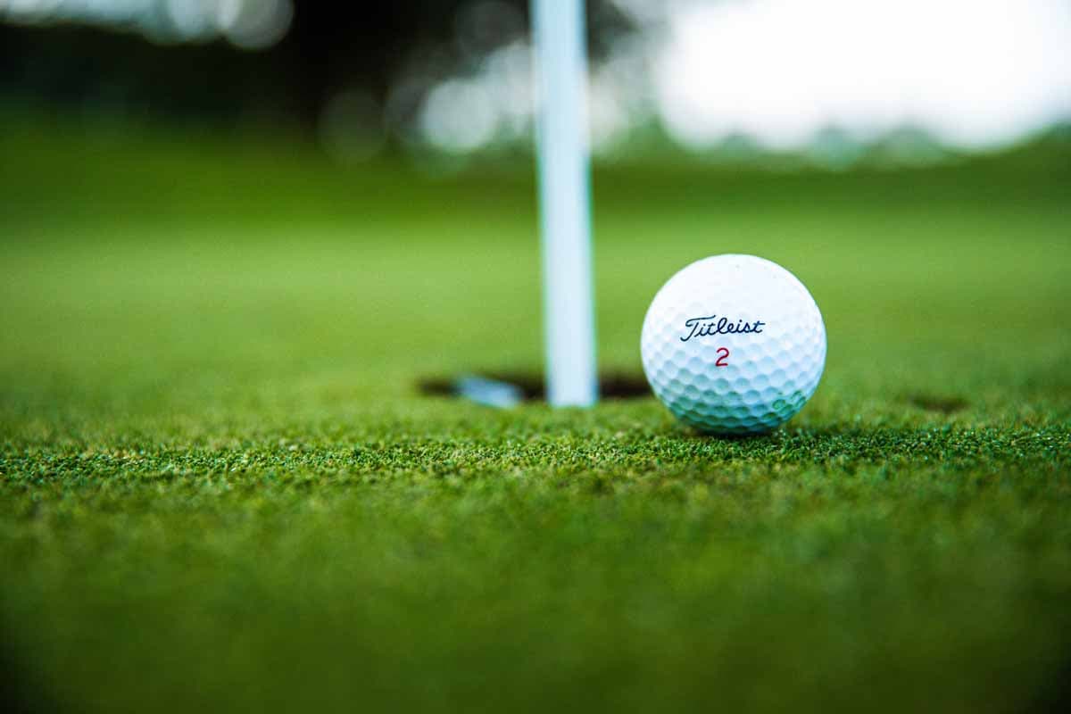 Golf ball resting beside the hole